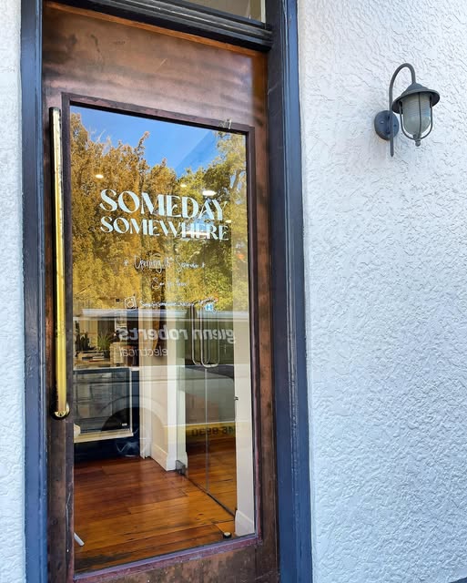 The café’s wooden door on Bridge Street with the Someday Somewhere wordmark painted on the glass.