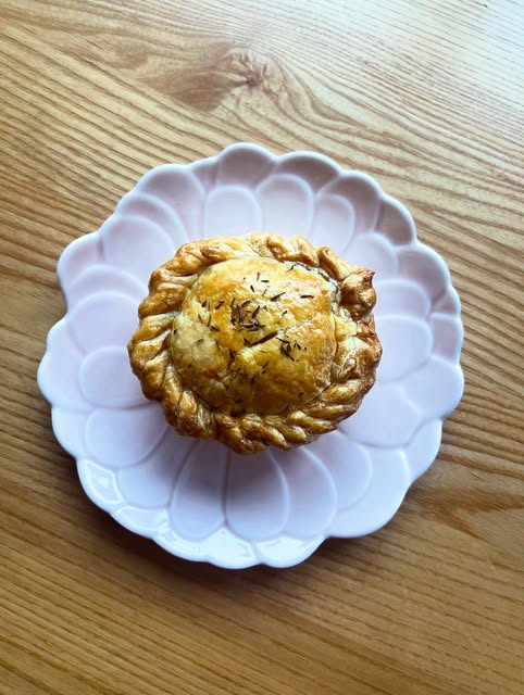 A hand-crimped golden pie on a pink scalloped plate.